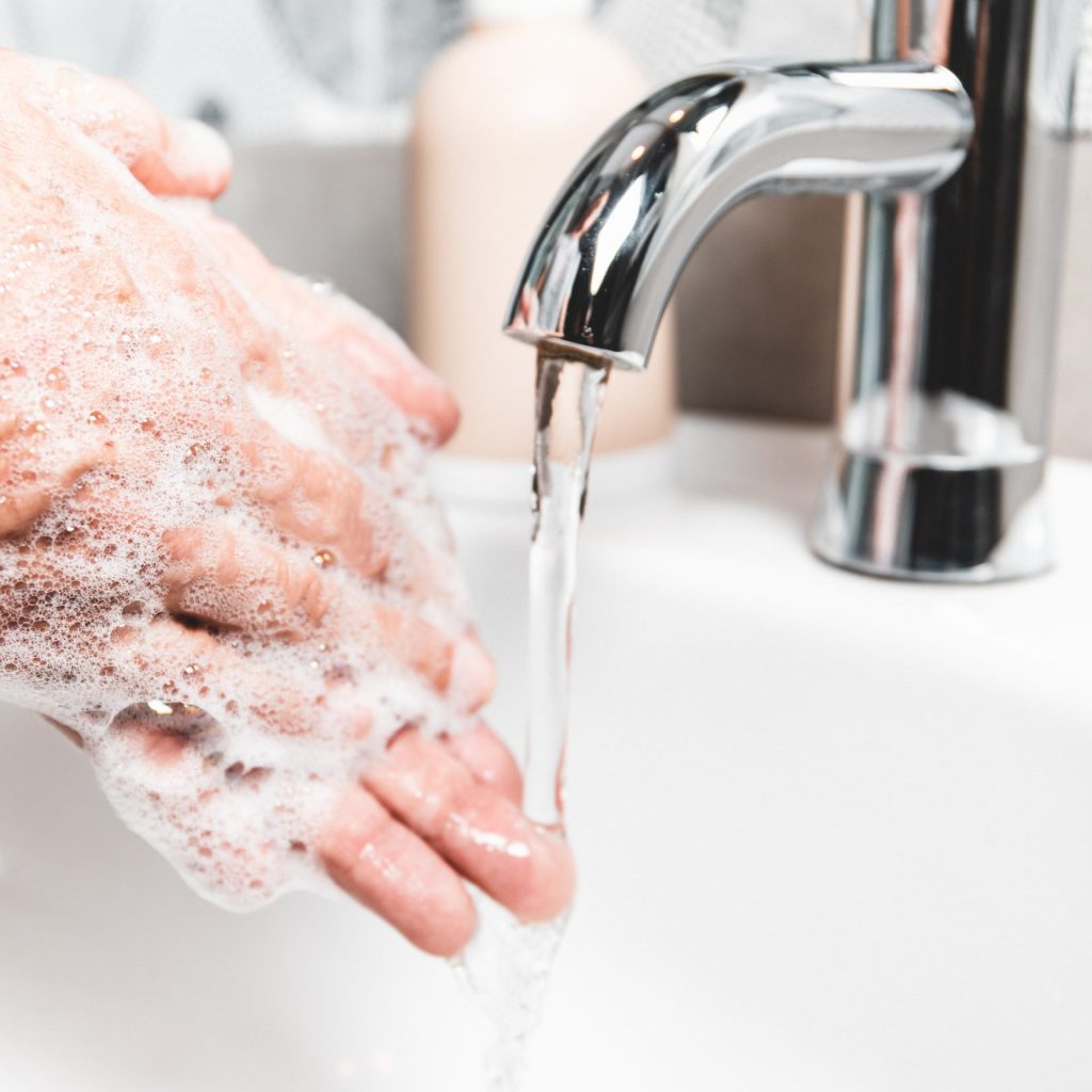 Person washing their hands with soap and hot water in the home